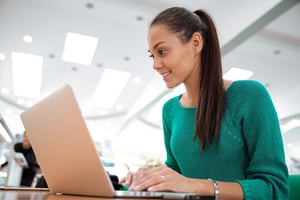 Portrait of a happy female student using laptop computer in university